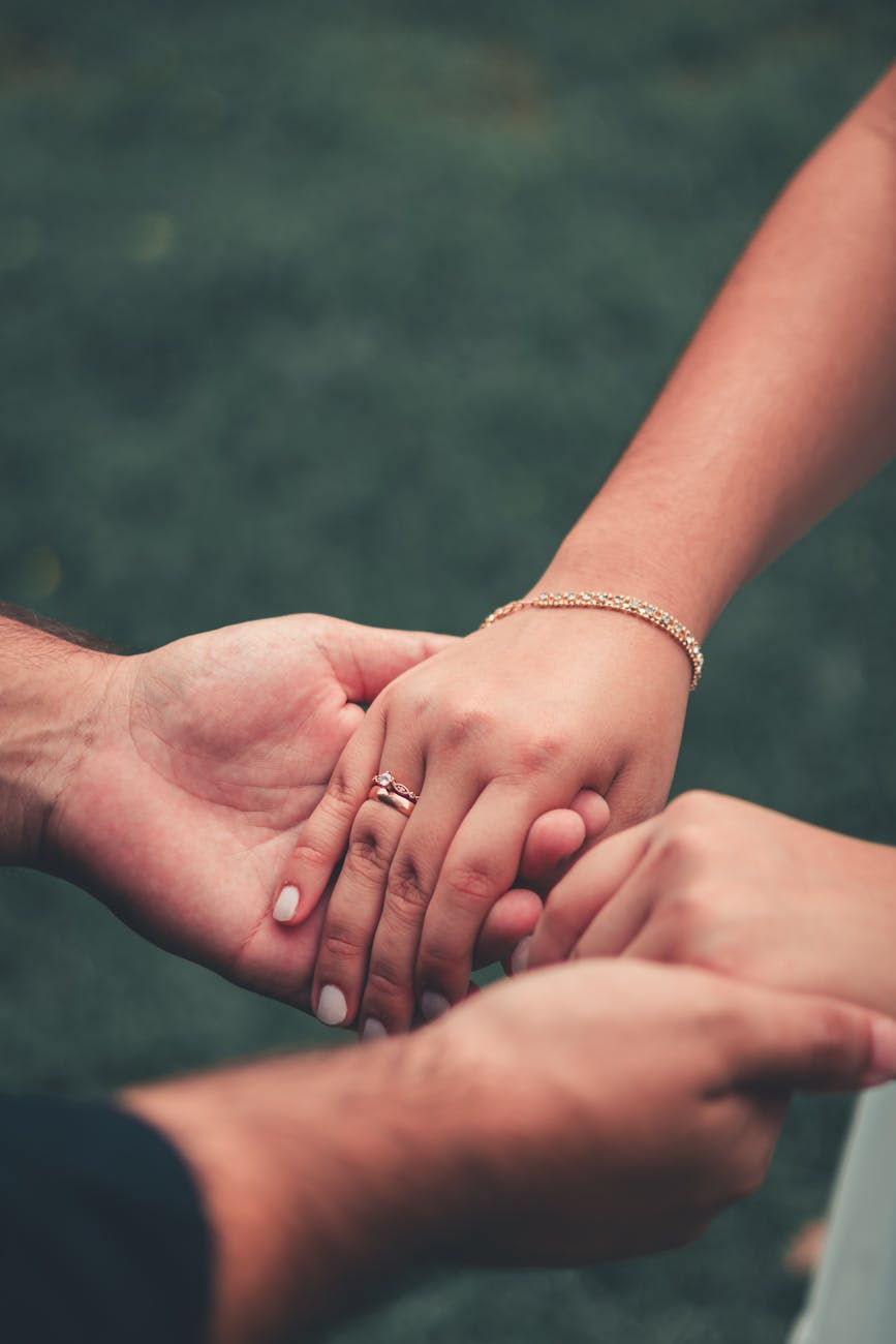 Intimate moment of a couple holding hands, symbolizing love and connection in an outdoor setting.